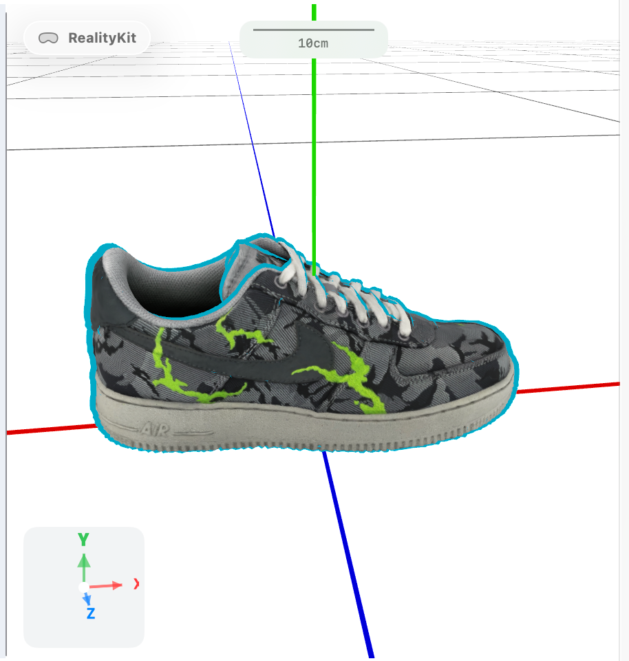 A 3D model of a Nike Air Force 1 sneaker with a black and grey camouflage pattern and neon green lightning bolt accents, displayed in Gantry: Scene Converter. The shoe features white laces, a grey sole with "AIR" branding, and a cyan outline indicating selection. A green vertical axis marker shows "10cm" scale above the shoe. The model rests on a white grid floor with red and blue axis lines, and a coordinate gizmo (showing Y, X, and Z axes) appears in the bottom-left corner.
